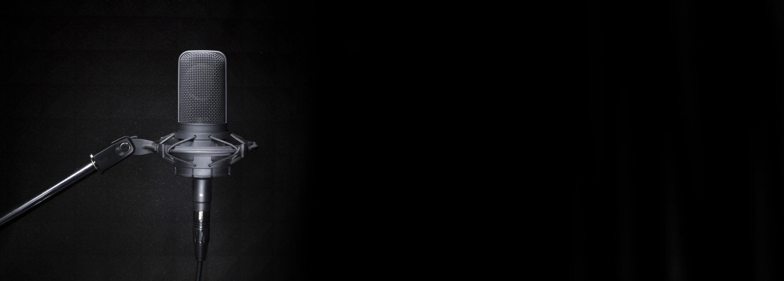 Professional studio recording microphone on the dark, black background with copy space for broadcast or recording studio banner